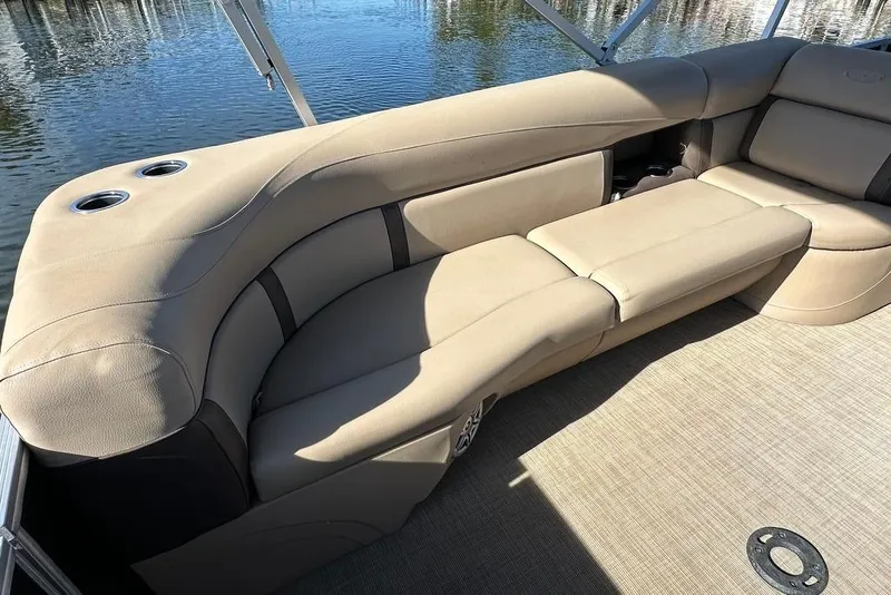 Slide: The Image of 2017 Harris Cruiser 220 boat interior with beige seating and cup holders, overlooking water. - 23