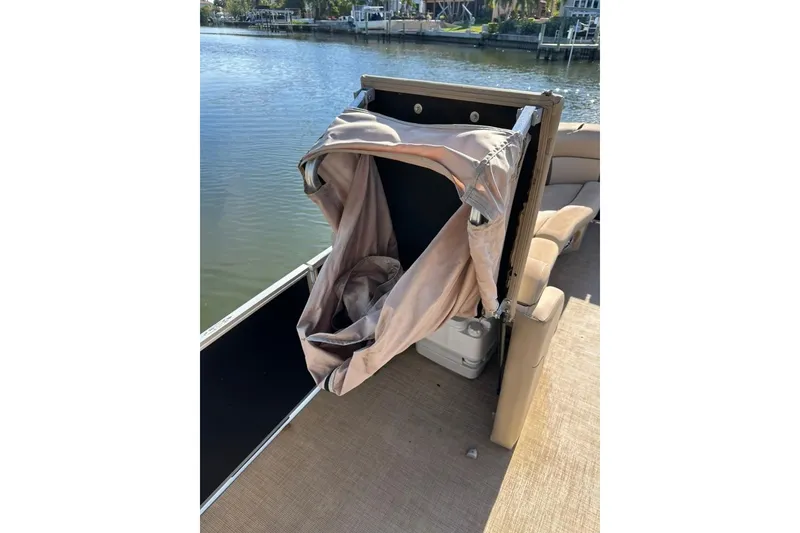 Slide: The Image of 2017 Harris Cruiser 220 boat with a folded canopy by the water. - 25