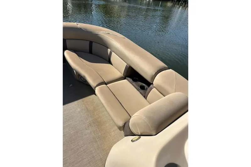 Slide: The Image of 2017 Harris Cruiser 220 boat interior with beige seating and cup holders by the water. - 28