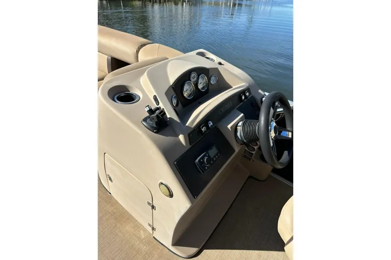 Slide: The Image of 2017 Harris Cruiser 220 boat dashboard with steering wheel and controls by the water. - 32