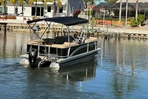 Slide: The Image of 2017 Harris Cruiser 220 pontoon boat on a calm waterway, featuring a black canopy. - 7