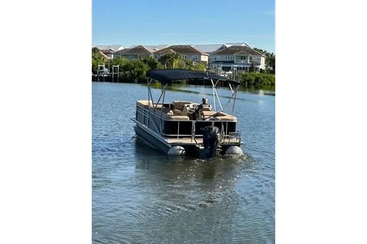 Slide: The Image of 2017 Harris Cruiser 220 pontoon boat on a calm lake with houses in the background. - 8