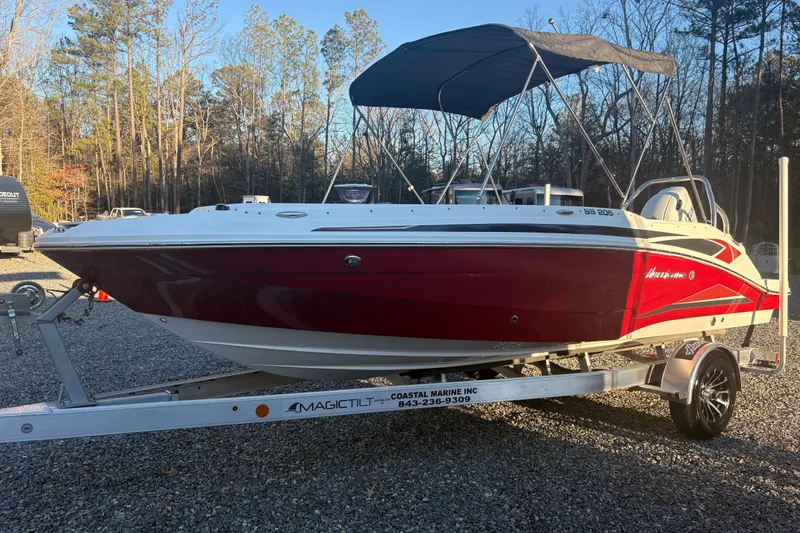 The Image of 2023 Hurricane SunDeck Sport 205 OB boat on trailer, red and white design, parked outdoors. - 0
