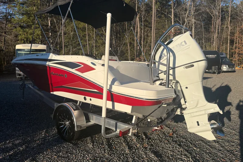 Slide: The Image of 2023 Hurricane SunDeck Sport 205 OB boat with Suzuki outboard motor, parked on a trailer. - 1