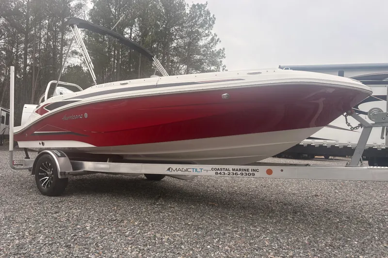 Slide: The Image of 2023 Hurricane SunDeck Sport 205 OB boat on trailer, red and white design, parked outdoors. - 19