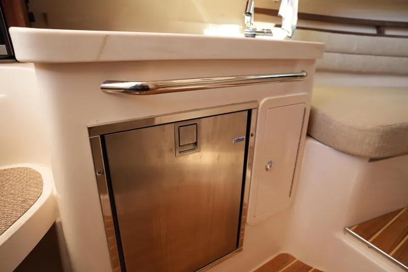 Slide: The Image of 2023 Grady-White Marlin 300 interior with stainless steel fridge and cushioned seating. - 56
