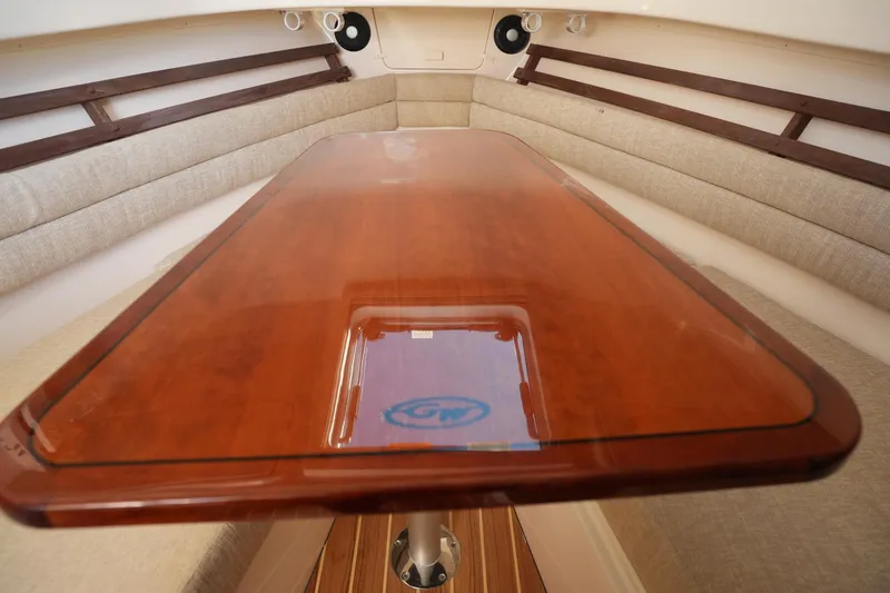 Slide: The Image of 2023 Grady-White Marlin 300 cabin interior with polished wooden table and cushioned seating. - 58
