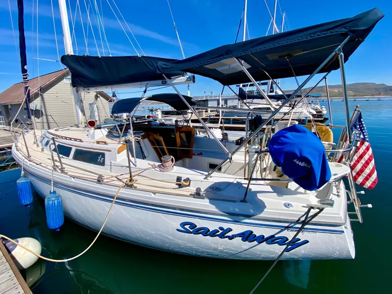 Slide: The Image of 1989 Catalina 36 sailboat docked, featuring blue cover and American flag. - 2