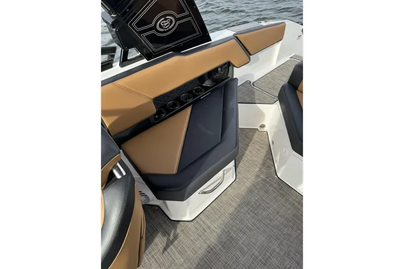 Slide: The Image of 2022 Cobalt R4 Surf boat interior with tan and black seating, cup holders, and water view. - 14