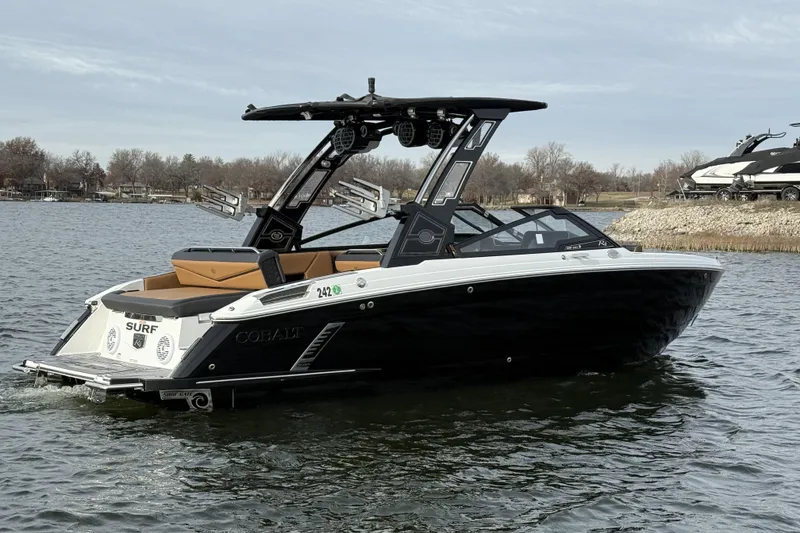 Slide: The Image of 2022 Cobalt R4 Surf boat on a calm lake, featuring sleek black and white design. - 5