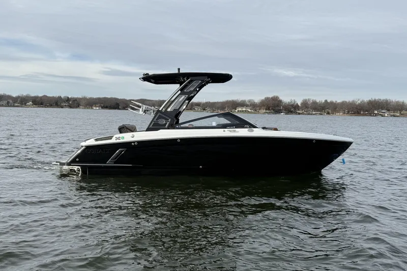 Slide: The Image of 2022 Cobalt R4 Surf boat on a calm lake, showcasing sleek black design. - 6