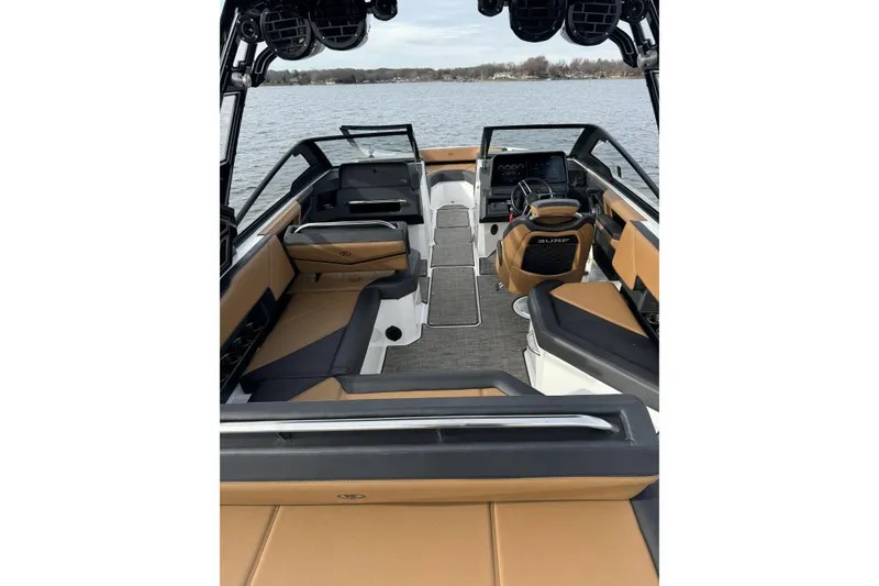 Slide: The Image of 2022 Cobalt R4 Surf boat interior with tan and black seating, on a calm lake. - 9