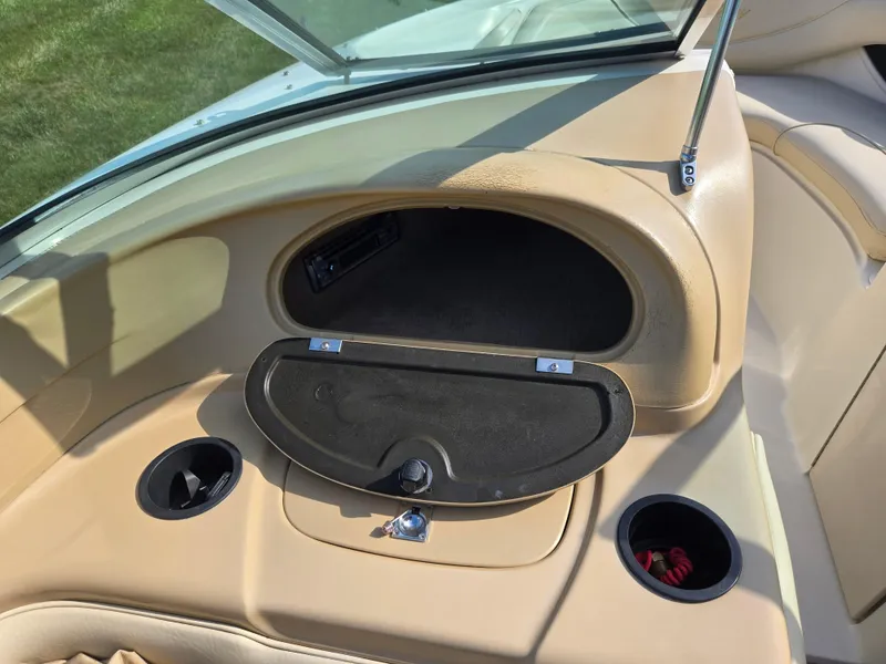 Slide: The Image of 1999 Sea Ray 210 BR boat dashboard with open glove compartment and cup holders. - 15