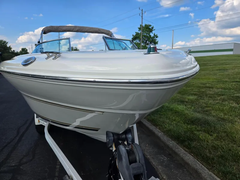 Slide: The Image of 1999 Sea Ray 210 BR boat on trailer, parked on a paved road with grassy surroundings. - 6