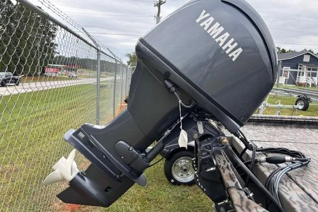Slide: The Image of 2026 Xpress XP170 boat with Yamaha outboard motor, parked near a chain-link fence. - 19