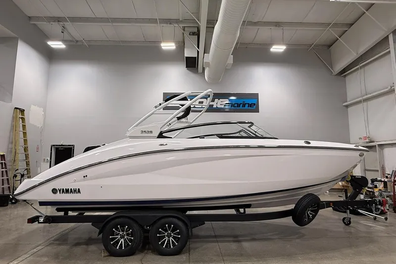 The Image of 2025 Yamaha Boats 252S in showroom, sleek design, white exterior, on trailer. - 0