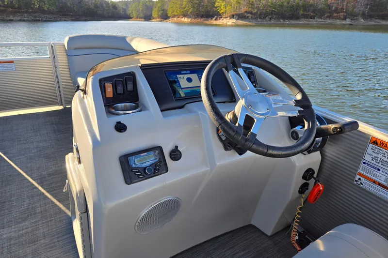 Slide: The Image of 2023 Bennington 22 SSR boat dashboard with steering wheel and control panel on a lake. - 18