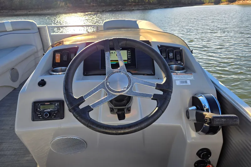 Slide: The Image of 2023 Bennington 22 SSR boat dashboard with steering wheel and controls on a lake. - 19