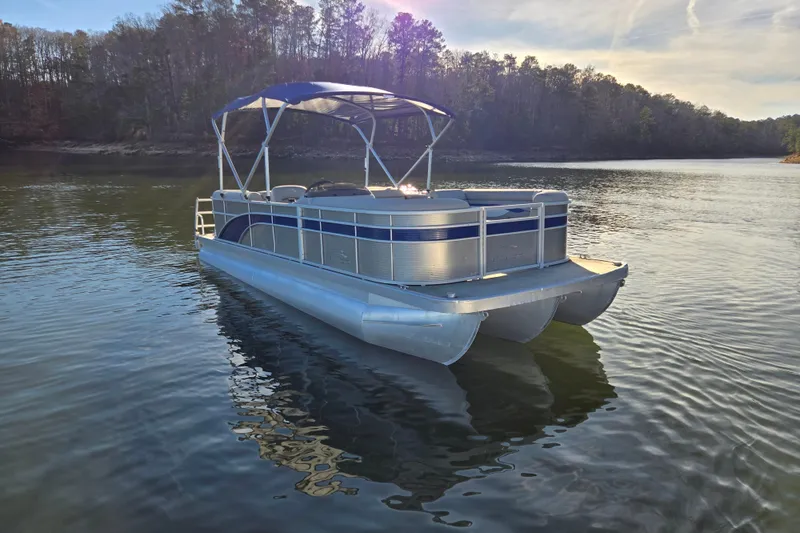 Slide: The Image of 2023 Bennington 22 SSR pontoon boat on a serene lake with forested shoreline. - 3