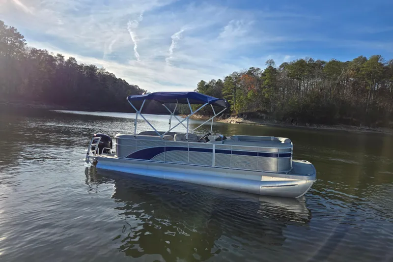 Slide: The Image of 2023 Bennington 22 SSR pontoon boat on a serene lake with forested shoreline. - 4