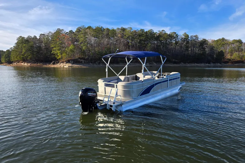 Slide: The Image of 2023 Bennington 22 SSR pontoon boat on a serene lake with forested shoreline. - 5