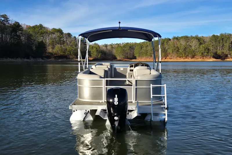 Slide: The Image of 2023 Bennington 22 SSR pontoon boat on a serene lake with forested shoreline. - 6