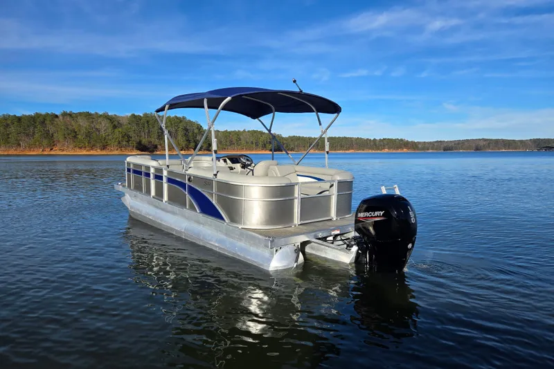 Slide: The Image of 2023 Bennington 22 SSR pontoon boat on a serene lake with a Mercury outboard motor. - 7