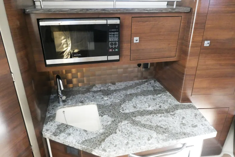 Slide: The Image of 2020 Boston Whaler 345 Conquest galley with granite countertop, sink, and microwave. - 18