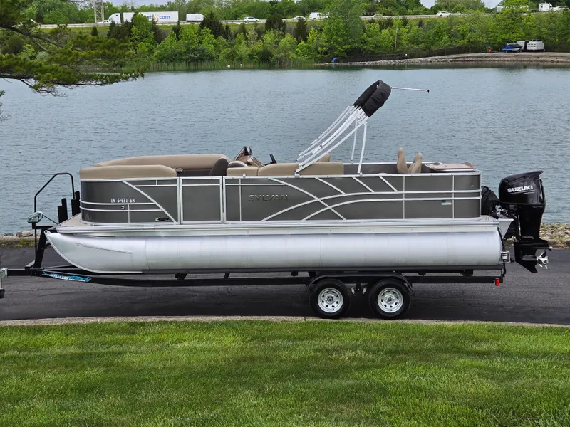 The Image of 2022 Sylvan Mirage Fish 822 Party Fish pontoon boat on trailer by a lake. - 0
