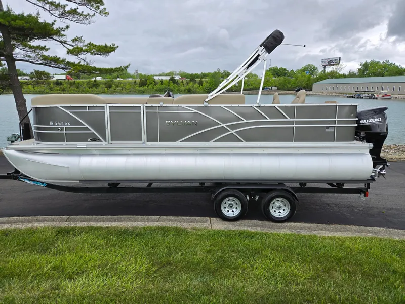 Slide: The Image of 2022 Sylvan Mirage Fish 822 Party Fish pontoon boat on trailer by a lake. - 9