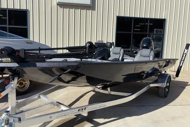 Slide: The Image of 2026 Xpress H18C Crappie boat in black, parked on a trailer outside a building. - 3