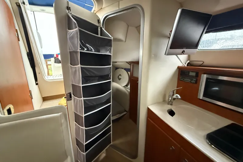 Slide: The Image of 2009 Bayliner 285 Cruiser interior with kitchenette, TV, and storage organizer. - 12