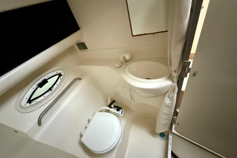 Slide: The Image of 2009 Bayliner 285 Cruiser bathroom with sink, toilet, and porthole window. - 15