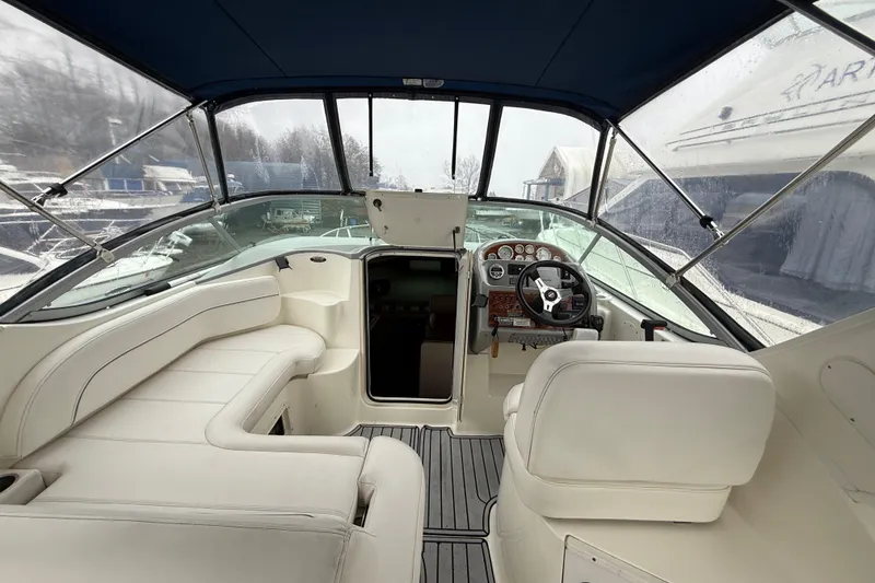 Slide: The Image of 2009 Bayliner 285 Cruiser interior with white seating and steering wheel, under blue canopy. - 4