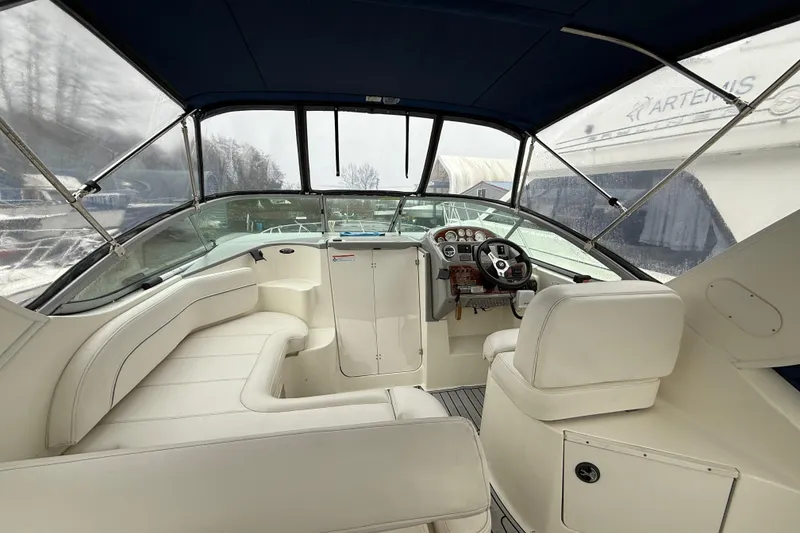 Slide: The Image of 2009 Bayliner 285 Cruiser interior with helm, seating, and dashboard under canopy. - 7