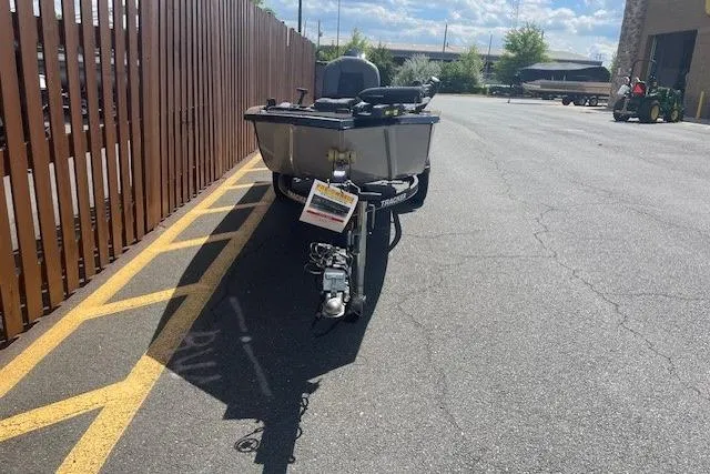 Slide: The Image of 2019 Tracker Panfish 16 boat parked on asphalt near a wooden fence under a sunny sky. - 4