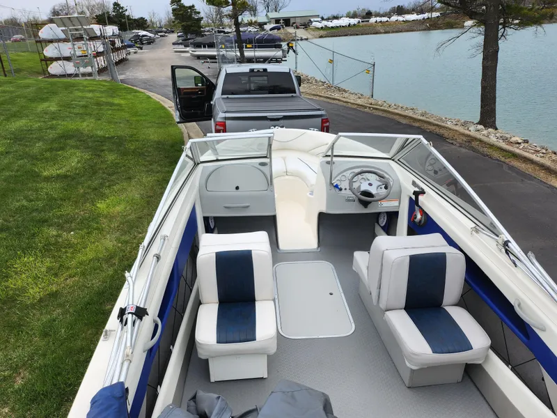 Slide: The Image of 2007 Bayliner Discovery 195 boat interior with seating, parked near a lake. - 10