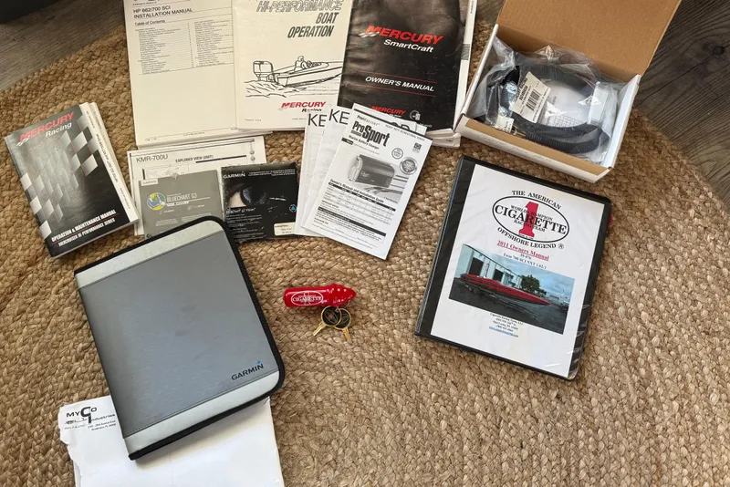 Slide: The Image of Assorted manuals and accessories for 2011 Cigarette 39' Top Gun Unlimited boat on woven mat. - 112