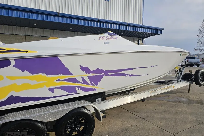 Slide: The Image of 2003 Baja 25 Outlaw boat with vibrant purple and yellow graphics on a trailer. - 10