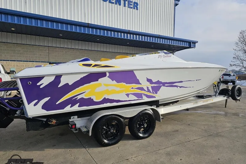 Slide: The Image of 2003 Baja 25 Outlaw speedboat with vibrant purple and yellow graphics on a trailer. - 11