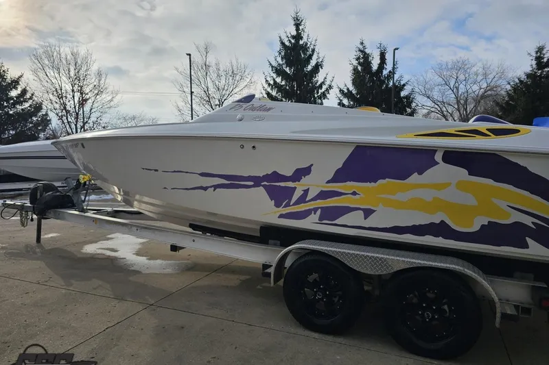 Slide: The Image of 2003 Baja 25 Outlaw boat with vibrant purple and yellow graphics on a trailer. - 21