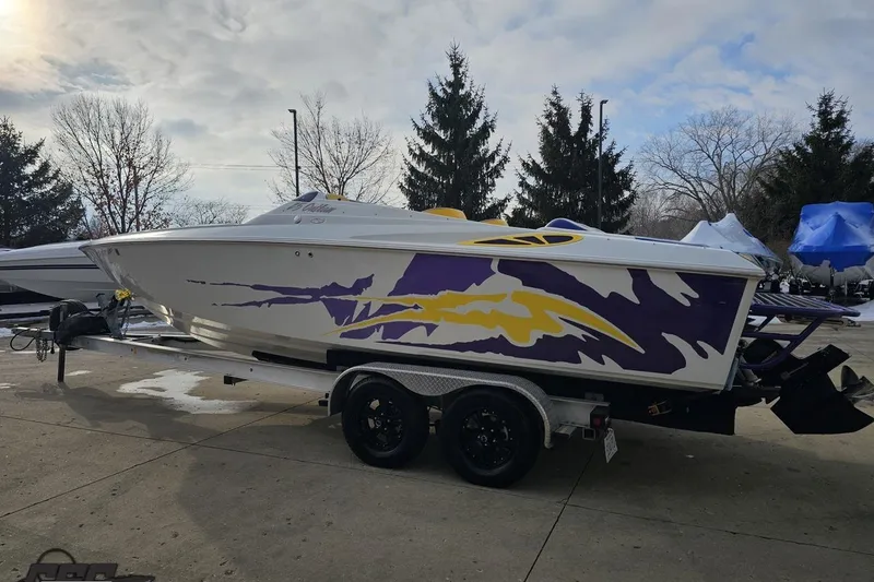 Slide: The Image of 2003 Baja 25 Outlaw speedboat with vibrant purple and yellow graphics on a trailer. - 22