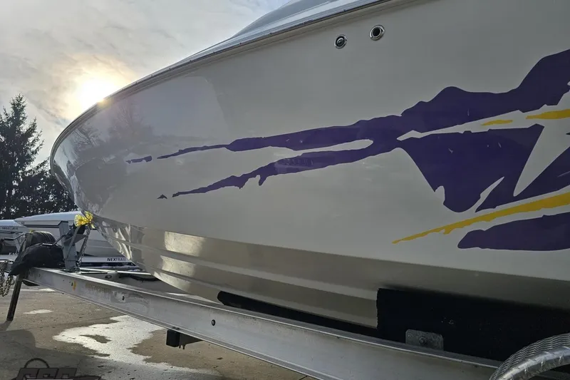 Slide: The Image of 2003 Baja 25 Outlaw boat on trailer with vibrant purple and yellow graphics. - 26