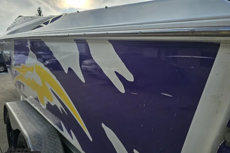 Slide: The Image of 2003 Baja 25 Outlaw boat with vibrant purple and yellow graphics on the side. - 28