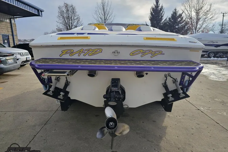 Slide: The Image of 2003 Baja 25 Outlaw boat with "PAID OFF" text on the stern, parked outdoors. - 30