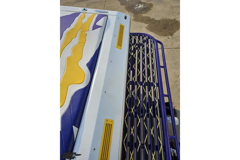Slide: The Image of 2003 Baja 25 Outlaw boat with vibrant yellow and purple design on deck. - 34