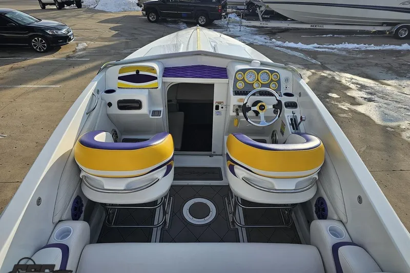 Slide: The Image of 2003 Baja 25 Outlaw boat interior with yellow and purple seating, steering wheel, and dashboard. - 38