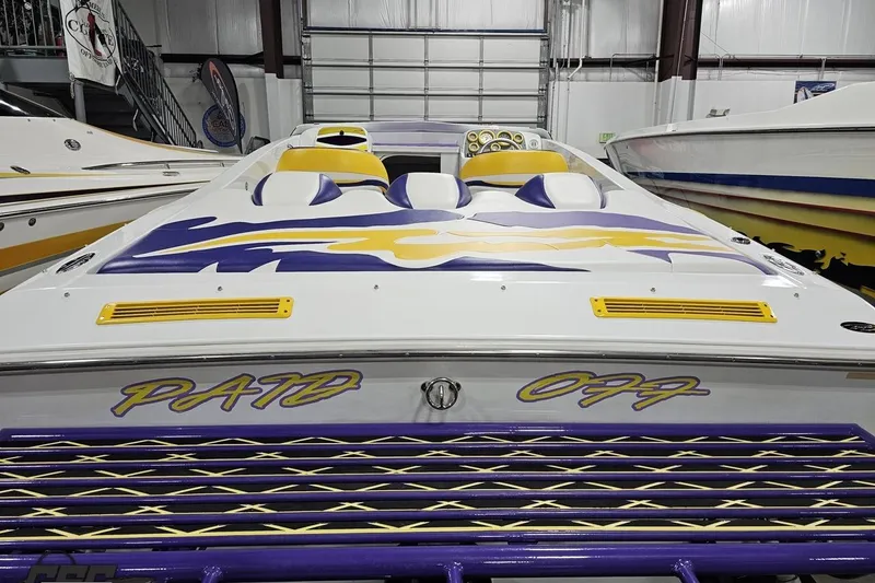 Slide: The Image of 2003 Baja 25 Outlaw speedboat with vibrant yellow and purple design in a showroom. - 45