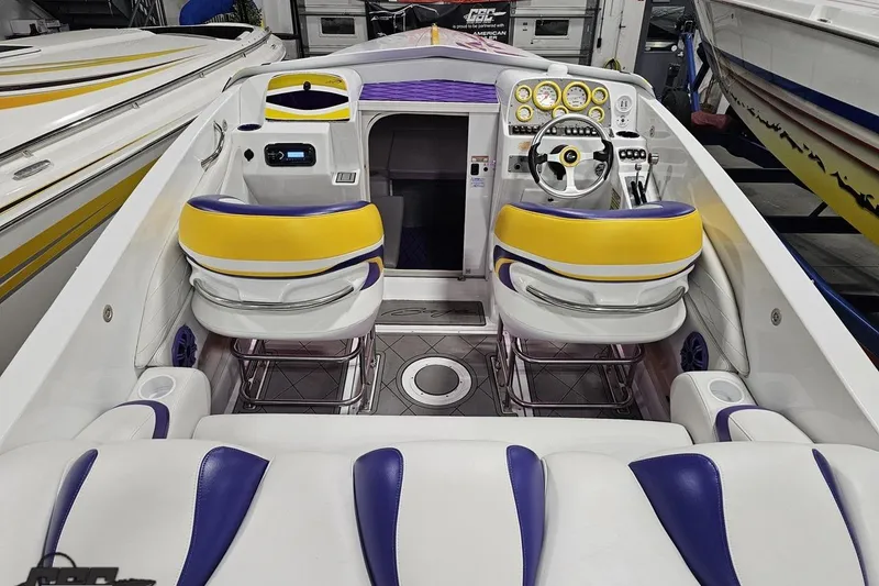 Slide: The Image of 2003 Baja 25 Outlaw boat interior with yellow and purple seating, steering wheel, and dashboard controls. - 50