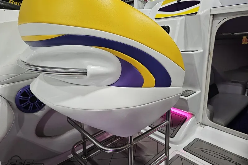Slide: The Image of 2003 Baja 25 Outlaw boat interior with vibrant yellow and purple seating design. - 58